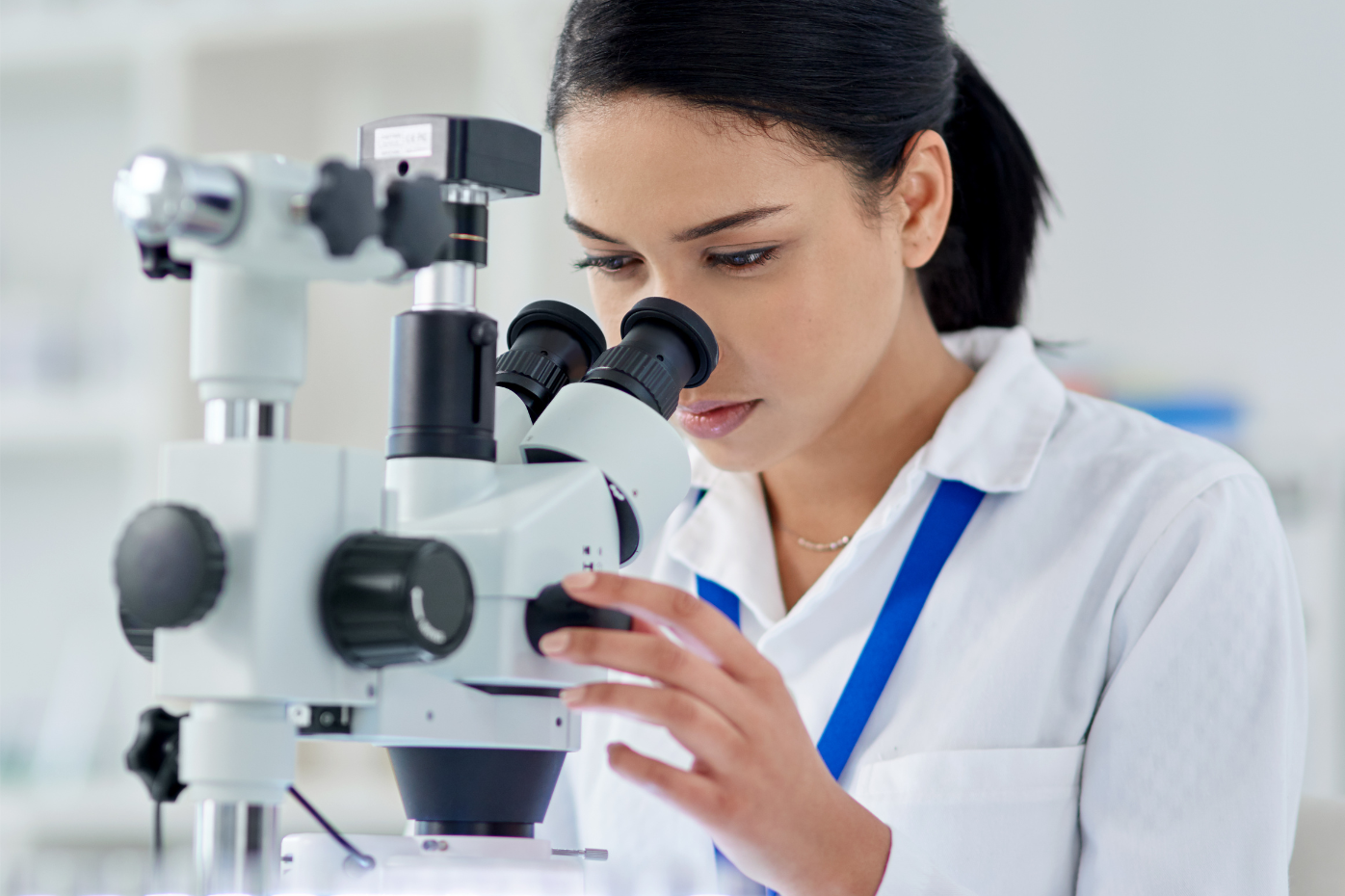 una joven investigadora frente a un microscopio