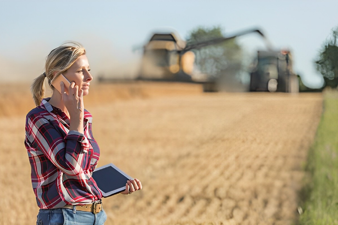 una mujer con un móvil y una tablet en una explotación agraria