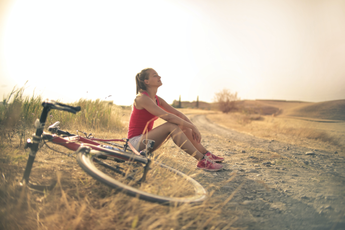 una mujer sentada en el campo junto a una bicicleta