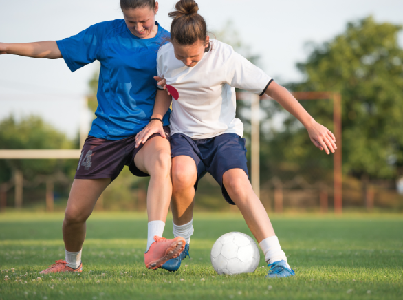 Dos jugadoras de fútbol se disputan la pelota en el campo durante un partido