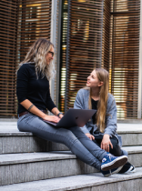 dos mujeres sentadas en una escalinata de un edificio