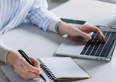 Una mujer trabajando con un portátil y una libreta