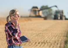 una mujer con una teblet y un móvil en una explotación agrícola