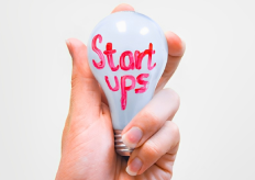 Una mano sujetando una bombilla con la palabra start ups escrita en ella
