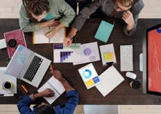varias personas en torno a una mesa consultando informes
