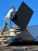 Una persona instalando un panel solar en un tejado