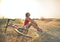 una joven sentada en un campo con una bicicleta a su lado