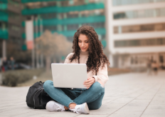 una joven con un ordenador portátil sentada en el suelo