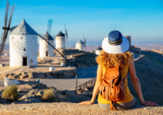 una joven sentada de espaldas contemplando unos molinos