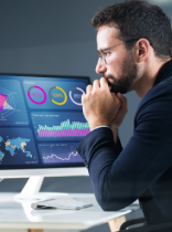 un hombre frente a pantallas con datos y estadísticas