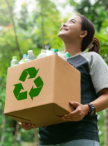 una chica con una caja de cartón con botellas de plástico