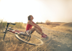 una mujer junto a una bicicleta sentada en el campo