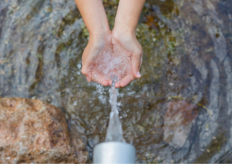 unas manos recogiendo agua en una fuente