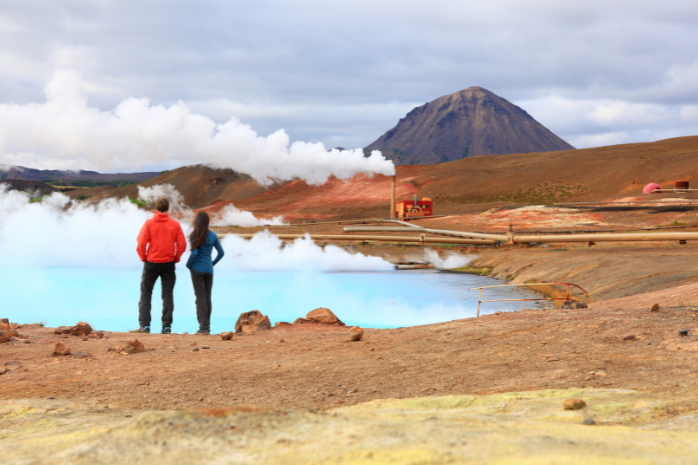 dos personas de espaldas frente a un campo de geotermia