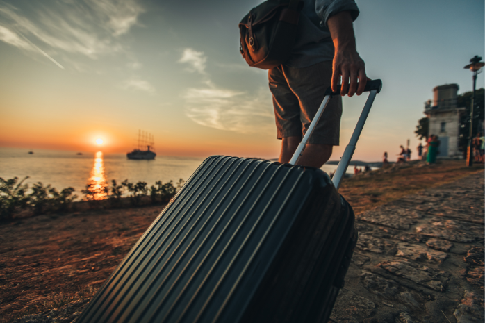 un turista cargando una maleta en un atardecer