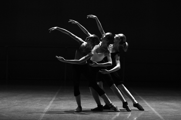 Tres bailarinas con los brazos extendidos en un escenario