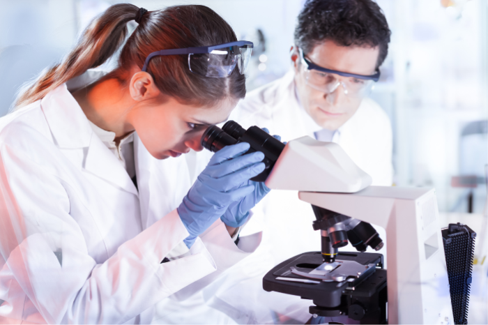 dos cient&iacute;ficos frente a un microscopio