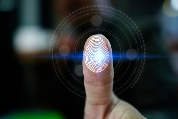 Un dedo sobre una cristal con reconocimiento de huellas