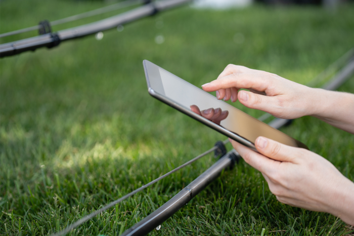 Unas manos con una tablet frente a un cultivo de regadío