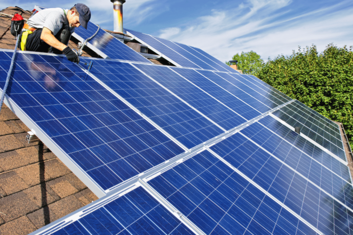 Instalador de paneles solares trabajando en un tejado.